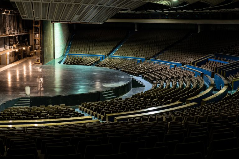An empty auditorium with the stage and institutional machinery of performance still in place.